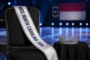 Empty Miss North Carolina USA chair with the titleholder’s sash and crown set aside.