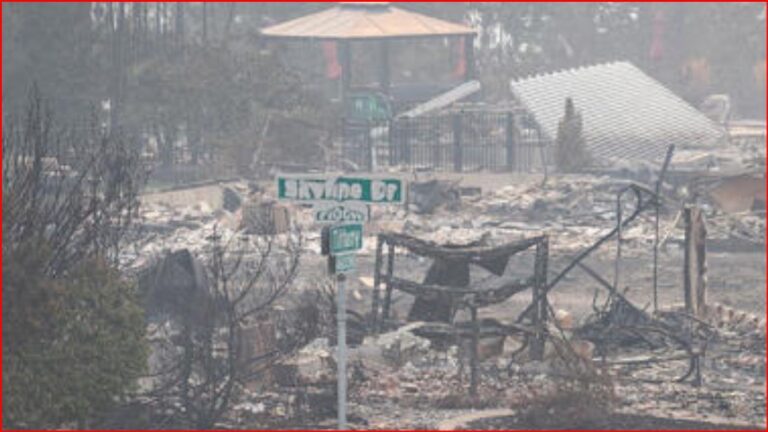 Charred ruins of a residential area after a fire, with a green street sign reading 'Limestone Dr' in the foreground.