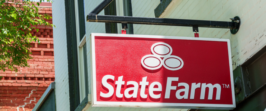 Red State Farm sign with the logo hanging outside a brick-and-wood storefront, indicating an insurance office