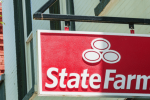 Red State Farm sign with the logo hanging outside a brick-and-wood storefront, indicating an insurance office