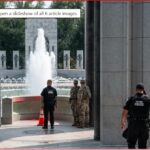 Uniformed police officers stand near a fountain at a memorial, with tall stone pillars surrounding.