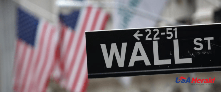 Close-up of a Wall Street street sign with blurred U.S. flags in the background.