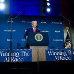 Donald Trump speaks behind a podium at the White House AI Summit, flanked by “Winning the AI Race” signs.