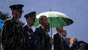Pete Hegseth stands alongside military officials in the rain during a Pentagon ceremony.