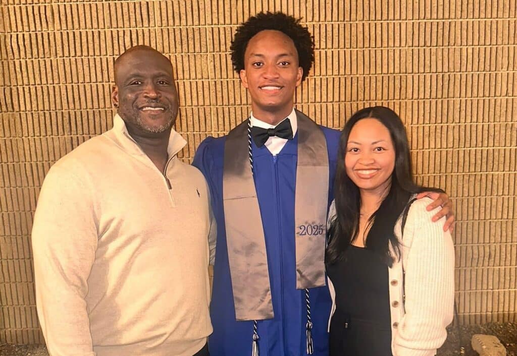 Nolan Wells, center, wearing a blue graduation gown in a family photograph. Download featured image