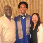 Nolan Wells, center, wearing a blue graduation gown in a family photograph. Download featured image