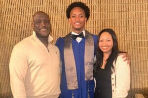 Nolan Wells, center, wearing a blue graduation gown in a family photograph. Download featured image