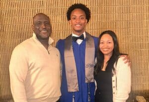 Nolan Wells, center, wearing a blue graduation gown in a family photograph. Download featured image