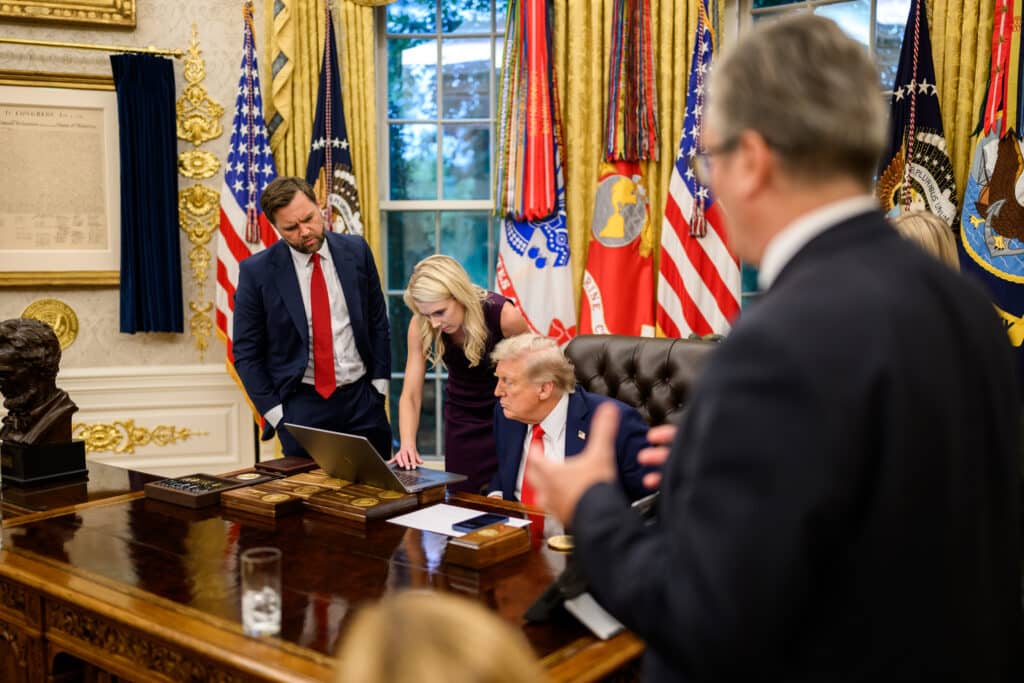 Donald Trump and Natalie Harp review a laptop in the Oval Office as JD Vance looks on.