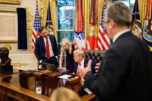 Donald Trump and Natalie Harp review a laptop in the Oval Office as JD Vance looks on.