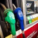 Green and blue fuel nozzles beside a pump offering diesel and gasoline.