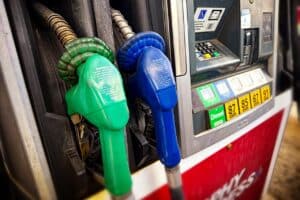 Green and blue fuel nozzles beside a pump offering diesel and gasoline.