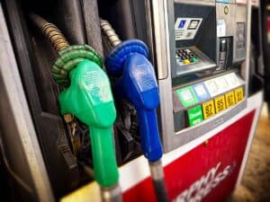 Green and blue fuel nozzles beside a pump offering diesel and gasoline.