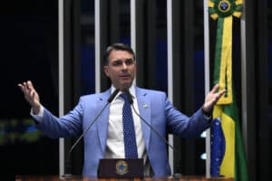 Flávio Bolsonaro speaks at Brazil’s Senate in Brasília, gesturing with both hands beside a Brazilian flag.