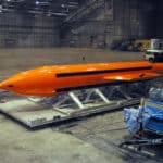 Orange GBU-43/B MOAB, nicknamed the mother of all bombs, resting on a transport platform inside a hangar.