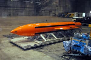 Orange GBU-43/B MOAB, nicknamed the mother of all bombs, resting on a transport platform inside a hangar.