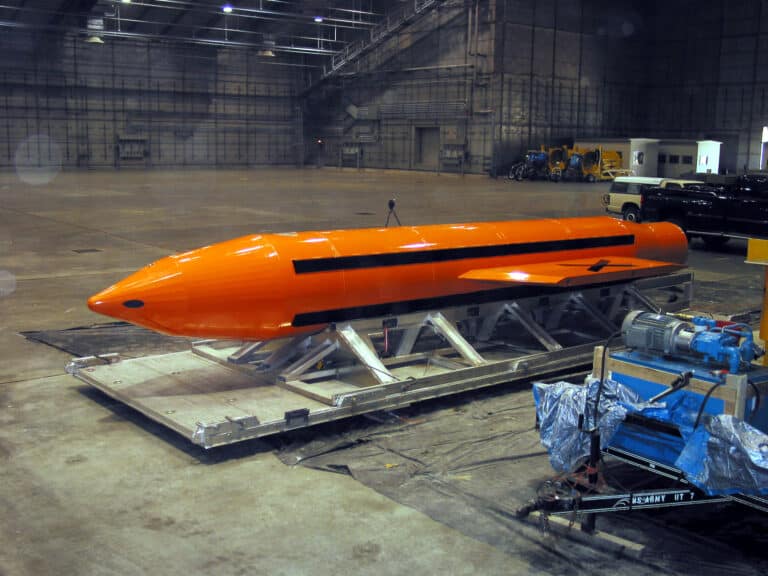 Orange GBU-43/B MOAB, nicknamed the mother of all bombs, resting on a transport platform inside a hangar.