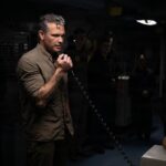 Pete Hegseth speaking into a handset aboard the USS Abraham Lincoln.
