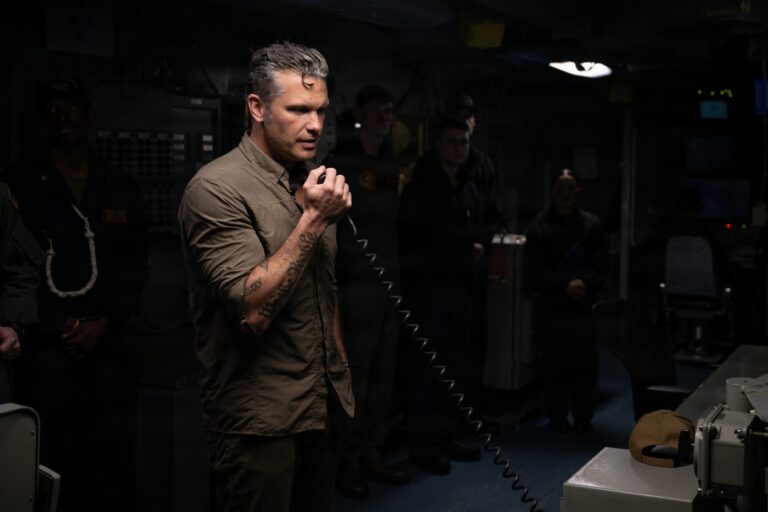 Pete Hegseth speaking into a handset aboard the USS Abraham Lincoln.